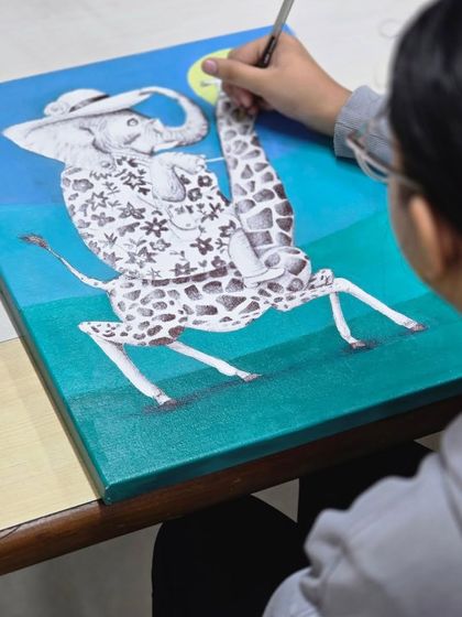 Another example of imaginative art from our young students. Here, an artist works on a ballpoint pen drawing of an elephant riding a giraffe.