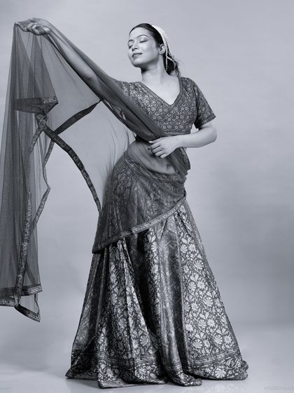 A black and white version of the model posing with her lehenga's dupatta.