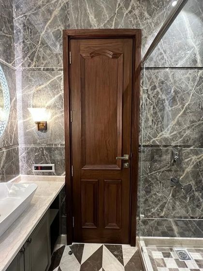This bathroom combines dark grey marble walls with a striking checkerboard floor. The round, backlit mirror and classic wall sconces add a touch of timeless elegance.