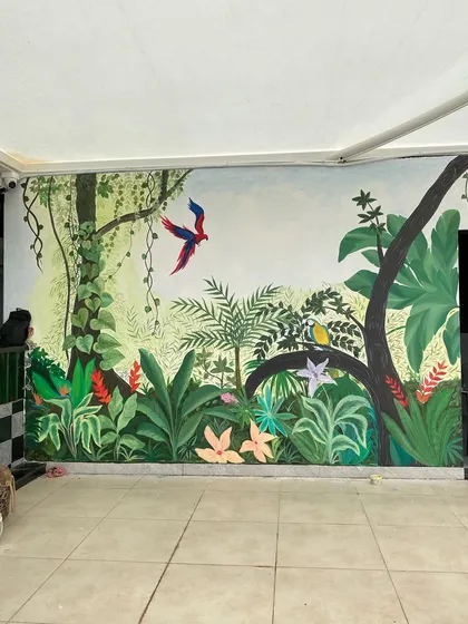 We call this our tropical paradise. We transformed the walls of a restaurant with a misty forest theme, covering even the doors to create a seamless, immersive jungle experience with colorful birds and lush greenery.