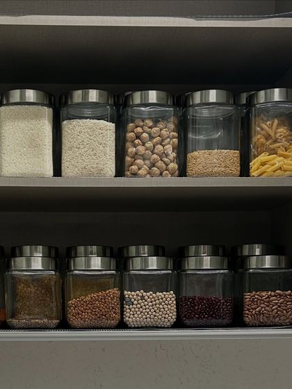 A pantry shelf organized with a variety of grains, from rice and chickpeas to pasta. This system ensures you can quickly see when you are running low on an item.