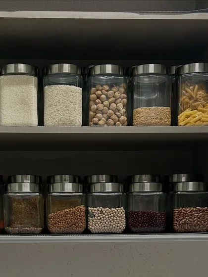 A pantry shelf organized with a variety of grains, from rice and chickpeas to pasta. This system ensures you can quickly see when you are running low on an item.