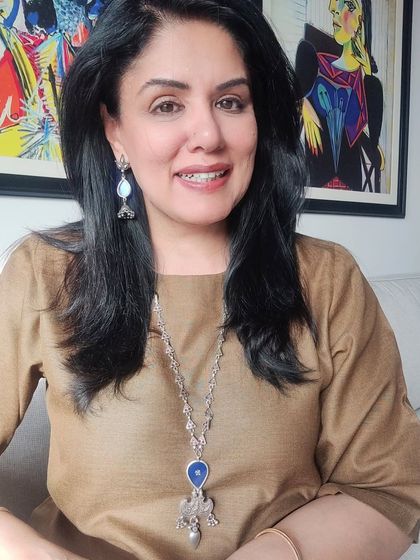 A close-up of the silver and blue necklace. The cool tones of the jewelry create a striking contrast against the warm brown of the dress, making for a memorable style statement.