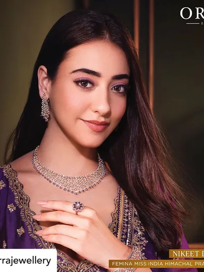 A close-up campaign image where the makeup details are clearly visible. The subtle purple eyeshadow and defined brows frame the face beautifully, drawing attention to the eyes and the jewelry.