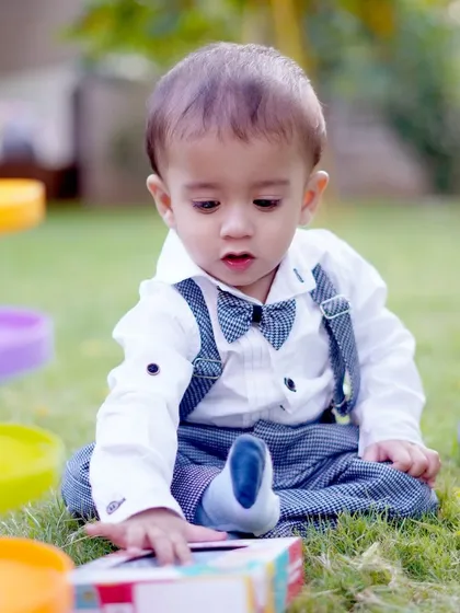 A focused toddler playing with a toy on the grass, a great example of our documentary style for kids' photography.