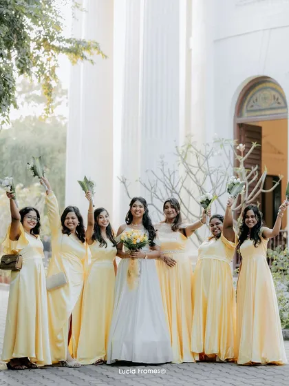 The bride and her joyful bridesmaids in their beautiful yellow dresses, celebrating together outside a classic Chennai church.