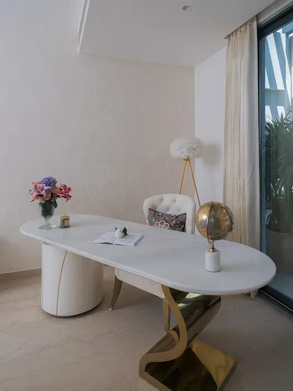A sculptural marble-top desk with fluid, curved gold legs anchors this workspace. It’s designed to be both a functional office desk and a beautiful piece of furniture that enhances the room's aesthetic.