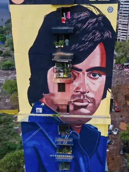 A close-up drone shot of the Big B mural, showing the incredible detail and how the artist cleverly integrated the building's windows and balconies into the portrait.