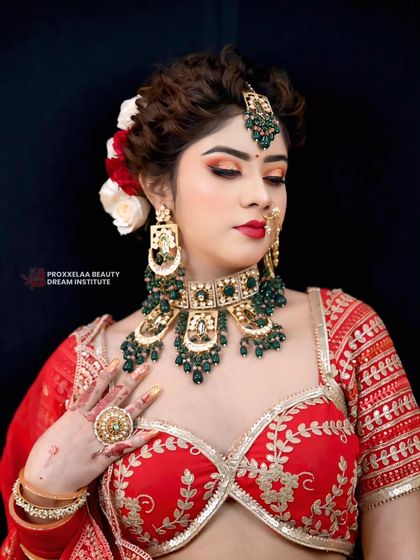 This bridal updo is intricately styled and adorned with red and white roses to match the lehenga. The hairstyle is designed to beautifully support the maang tikka and heavy earrings.