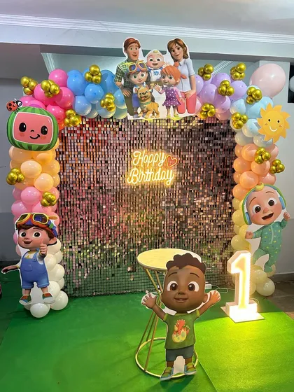 A full view of the Cocomelon party decor, showing the balloon columns and the large light-up number '1'.