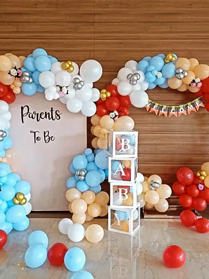 A "Parents To Be" decoration perfect for a welcome home party or baby shower. The setup includes a balloon arch in red, blue, and cream, with "BABY" blocks and "OH BOY" foil letters.