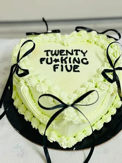 A trendy heart-shaped cake with black ribbons, perfect for a 25th birthday.