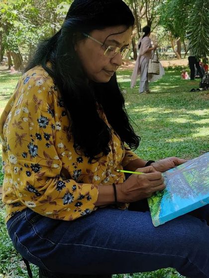 Deep in concentration, adding details to a landscape painting during a live session at the park.