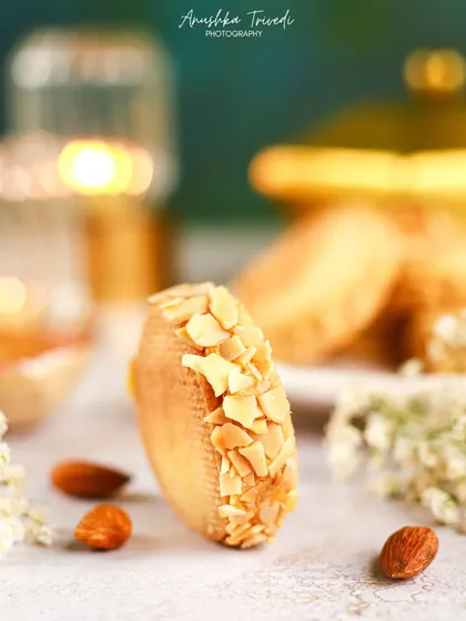 A creative shot of an almond cookie, with a beautiful bokeh effect from a candle in the background. This artistic approach creates a magical and festive mood.