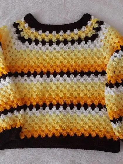 A flat-lay of the Trinity Sweater, showcasing the top-down construction and vibrant color pattern.