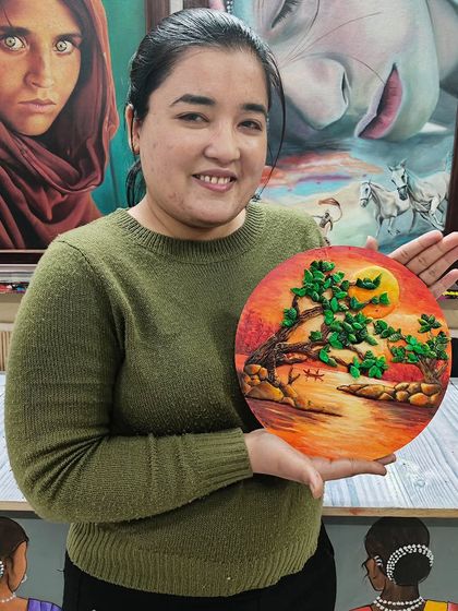 A student holding her beautiful Shilpkar art piece, a 3D landscape on a circular base. Shilpkar clay is a versatile medium for creating detailed models.
