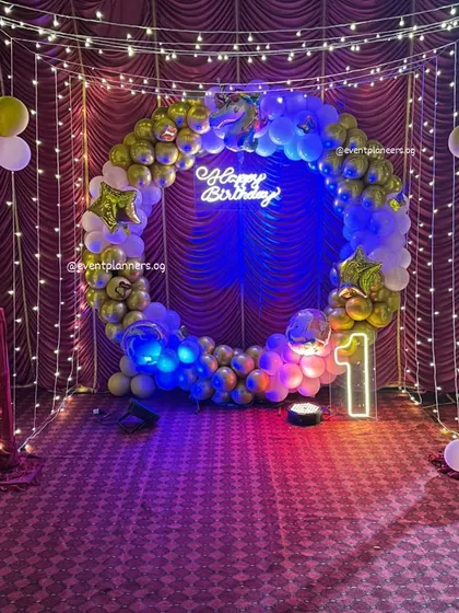 I create immersive photo zones that your guests will love. This birthday setup features a full balloon ring, a 'Happy Birthday' neon sign, and a canopy of fairy lights, creating a dreamy and enchanting space for photos.