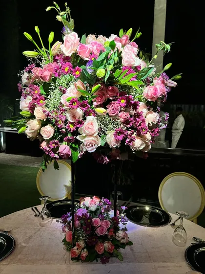 A tall, vibrant centerpiece of pink and purple flowers, designed to add height and a pop of color to the reception tables.