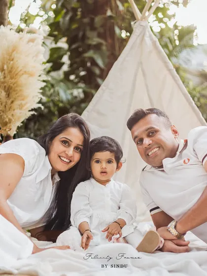 A happy family of three enjoying a relaxed moment during a boho-themed outdoor photoshoot. The teepee and natural setting create a perfect backdrop for capturing authentic family connections.