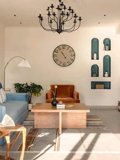 This living room was designed for a single doctor, reflecting her vibrant personality. I balanced a calming blue sofa with a rich, rust-colored armchair and created visual interest with a series of deep teal arched niches for displaying personal treasures.