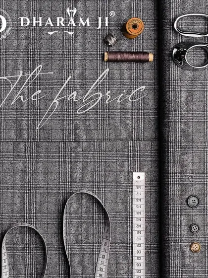 The foundation of any great suit is the fabric. Here you see a classic grey plaid cloth laid out with the tools of the trade, ready to be transformed.
