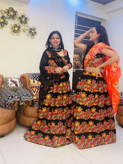 Two models wearing matching black floral embroidered lehengas, perfect for friends or sisters celebrating Navratri together.