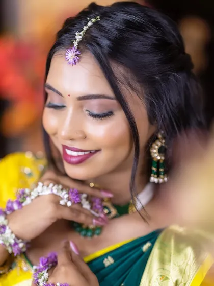 A close-up of a Haldi look, focusing on the beautiful magenta lip color that contrasts with the yellow and green outfit. The floral maang tikka adds a perfect touch.