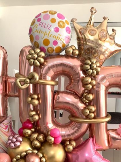 A stunning "HBD" balloon bouquet in rose gold. This intricate arrangement features a large crown, foil balloons, and smaller accent balloons, creating a luxurious and celebratory centerpiece.