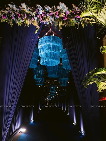 We believe the event experience begins at the entrance. This immersive walkway, featuring a tunnel of glowing blue chandeliers and dramatic drapery, creates a grand and memorable first impression for guests attending an exclusive corporate function or evening gala.