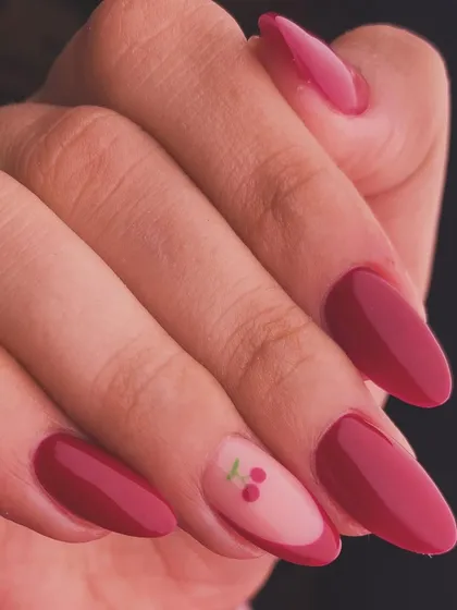 A simple yet sweet design with a deep red polish and a single accent nail featuring a pair of cherries.