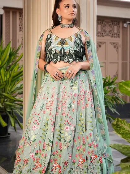 A three-quarter shot of the mint green lehenga, set against lush greenery that complements the outfit's colors. It shows the versatility of the outfit for both indoor and outdoor events.