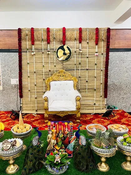I love creating rustic and earthy themes like this one for a baby shower. The backdrop is made from natural woven mats, decorated with jasmine and red flower garlands, perfectly framing the seer plates which feature peacock motifs and a variety of traditional offerings.