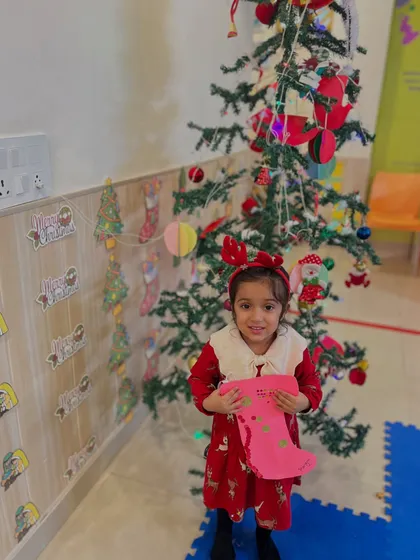 A girl in a red dress proudly displays the pink stocking she created.
