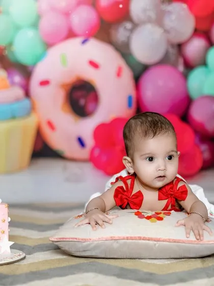 A little princess is on her way to rule the world! A beautiful baby girl in front of a cake in our candy-themed studio.
