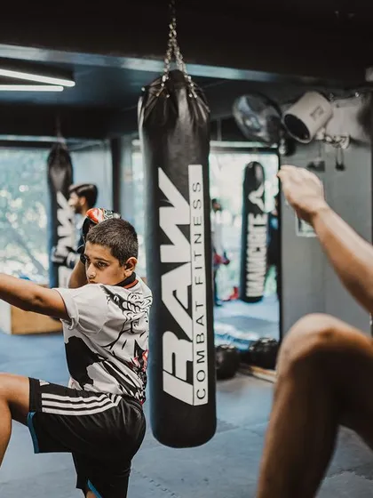 A coach and a young student practice the Wai Kru together, passing down the traditions of the sport.