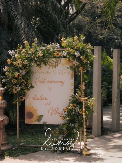 A beautiful welcome sign for a sunflower-themed Haldi ceremony, framed by a floral arch.