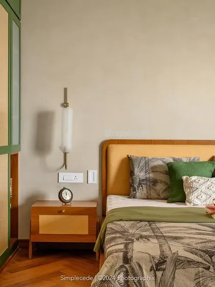 A detail of the master bedroom in 'Cover me in Sunshine', showing the custom bedside table and the interplay of green, rattan, and wood tones.