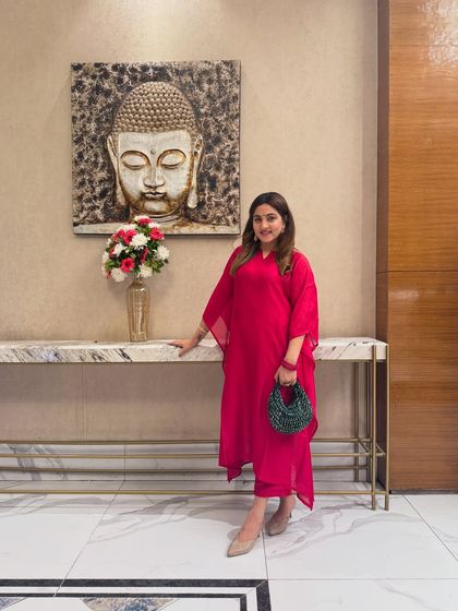 Posing against a serene backdrop, this pink kaftan outfit feels both luxurious and relaxed. The color combination with the green bag is a testament to smart, color-theory-based styling.