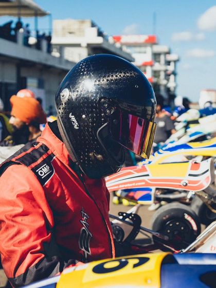 A driver in a black helmet, preparing for his session.