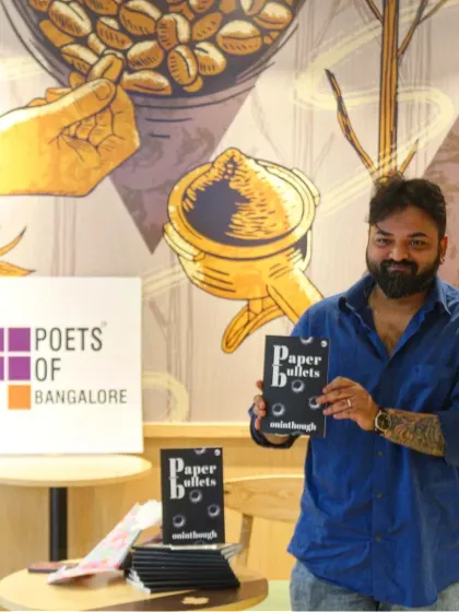 Author Oninthough proudly presenting his book, "Paper Bullets," next to our Poets of Bangalore branding.