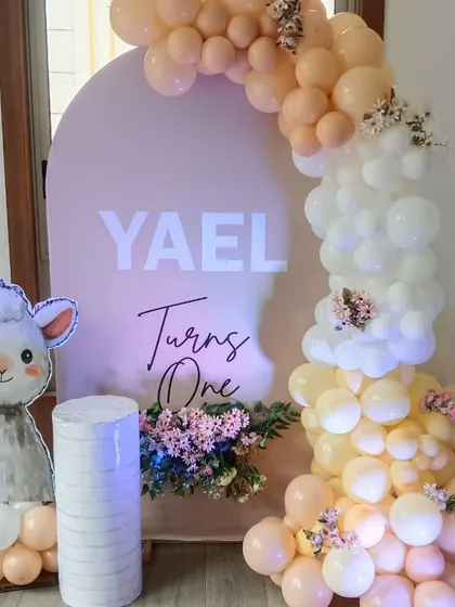 A sweet lamb-themed first birthday for Yael. The decor includes a custom backdrop, a cute lamb cutout, and a beautiful balloon arch in pastel shades.