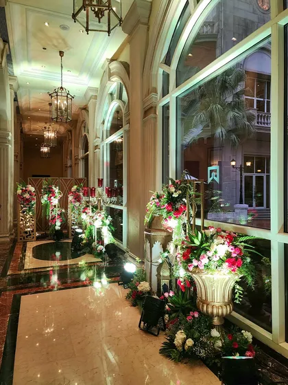 An elegant hallway at the Sufi Night event, lined with ornate floral arrangements in golden urns and traditional lanterns. This shows our commitment to transforming the entire event space.