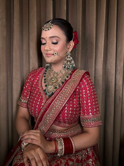 A side profile highlighting the heavy jhumkas and delicate nath that are part of this complete bridal set.