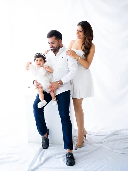 A picture-perfect family moment. Dressed in classic white, this family of three radiates happiness and love in a simple, timeless studio portrait.
