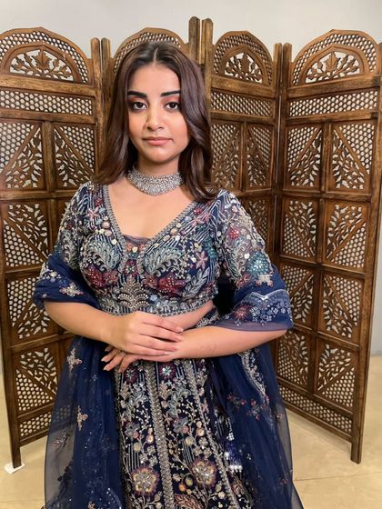 A close-up of the model in the navy blue lehenga, showing the incredible detail of the embroidery and the flattering neckline.