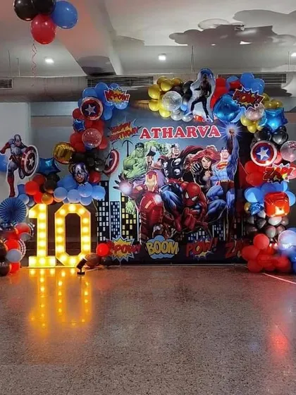 A full-scale Avengers superhero theme for a 10th birthday party. This setup includes a large printed backdrop of the city skyline, character cutouts, and a '10' marquee light.