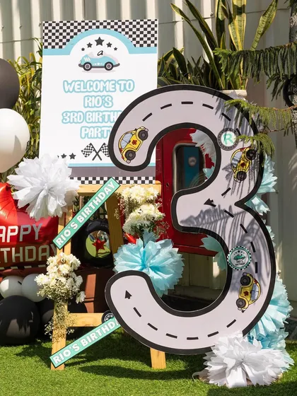 A close-up of the custom "3" sign, cleverly designed to look like a racetrack. These personalized details make each party unique and special.