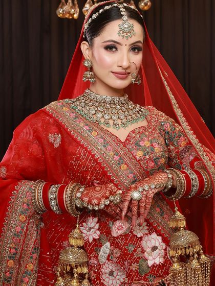 A full view of a bride's stunning look, with her red lehenga, heavy jewelry, and detailed mehandi creating a picture of perfection.