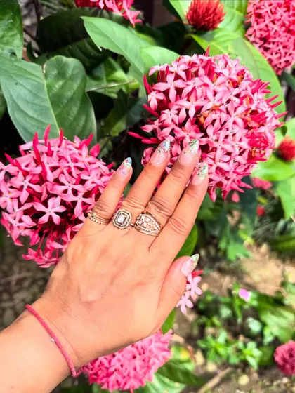 The perfect vacation nails. This design features a sheer base with a sprinkle of green glitter at the tips, looking fresh and beautiful against a backdrop of pink flowers.