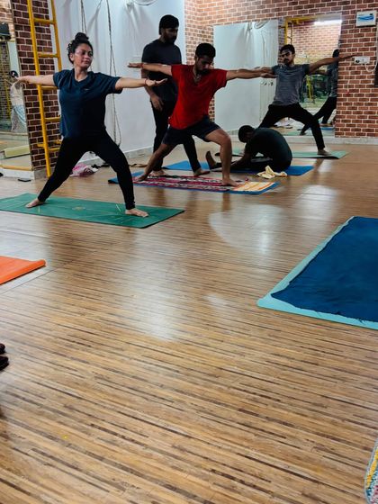 Guiding a student in Virabhadrasana II (Warrior II) to ensure their arms are parallel to the floor and their stance is strong and stable.